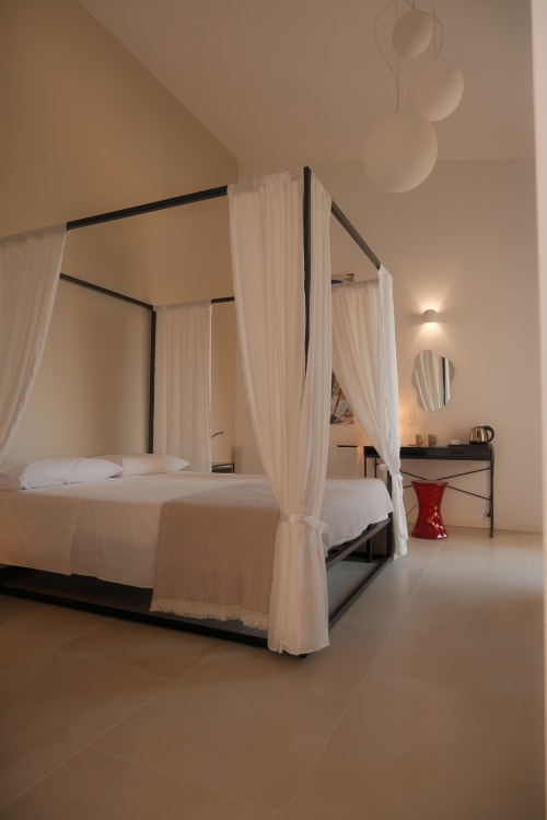 Luxurious canopy bed with white curtains in the Amira room at Nafura hotel in Raffadali, Agrigento, Sicily