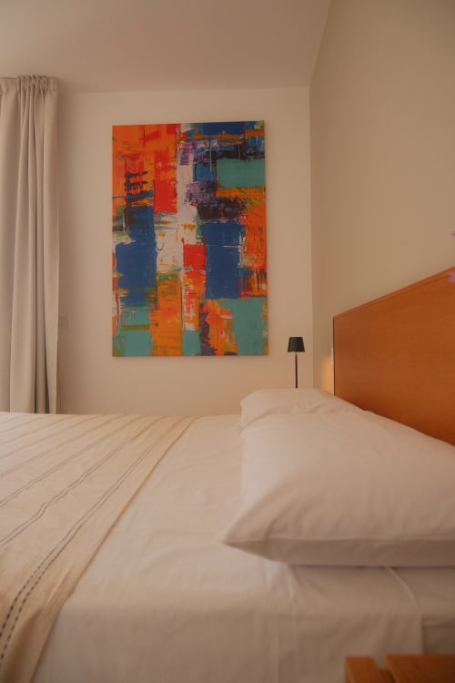 Modern bedroom at Nafura hotel in Raffadali with colorful abstract artwork, orange headboard, and white bedding overlooking