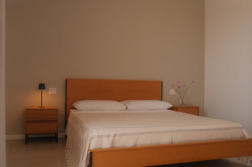 Modern bedroom at Nafura hotel in Raffadali with wooden bed, side table, and minimalist decor