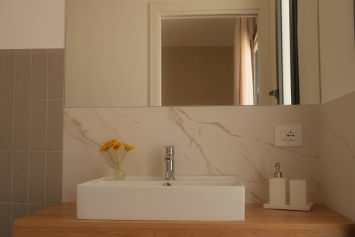 Modern bathroom sink at Nafura Hotel in Raffadali with marble backsplash and wooden countertop