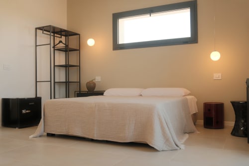 Modern minimalist bedroom at Nafura Hotel Farah room in Raffadali with bed, metal shelving, and ambient lighting