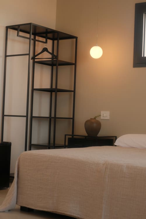 Nafura hotel room Farah in Raffadali with bed, black metal shelving unit, pendant light, and beige walls