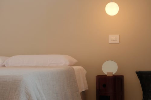 Bedroom at Hotel Nafura in Raffadali with bed, nightstand lamp, wall light, and electrical outlet