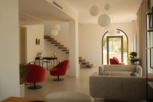 Modern Nafura hotel lobby in Raffadali featuring red accent chairs, floating stairs, and natural lighting
