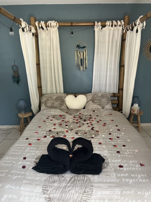 Lit à baldaquin romantique avec rideaux blancs, oreillers cœur et pétales de rose à la Chambre Love 4 étoiles Mb Room à Puget-sur-Argens