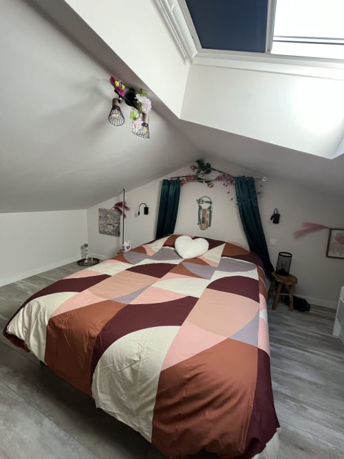 Chambre mansardée moderne avec literie à motifs géométriques, puits de lumière, draperies noires et décor floral - Mb Room 4