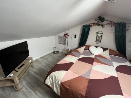 Chambre mansardée douillette avec linge de lit géométrique coloré, TV et vue sur le jardin à l'hôtel 4 étoiles Mb Room de Puget-sur-Argens