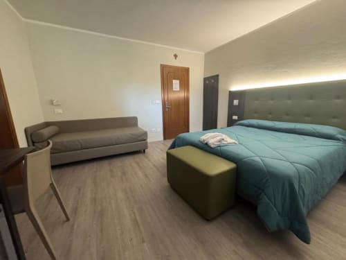 Camera tripla moderna all'hotel NOI di Vergato con letto matrimoniale, divano e pavimento in legno