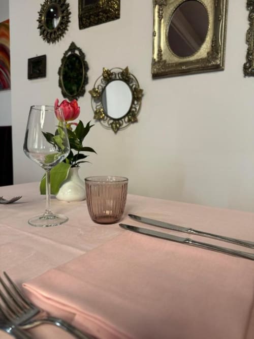 Elegante tavolo da pranzo in albergo con tovaglia rosa, calice di vino e composizione floreale rossa al NOI DI EVERT a Vergato, Italia