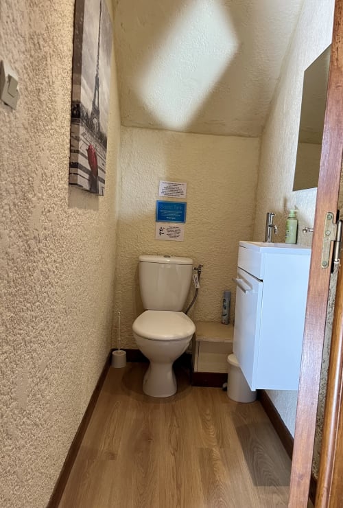 Petite salle de bain au Gîte La Vieille Ferme de La Doinie avec toilettes, lavabo blanc et murs couleur crème