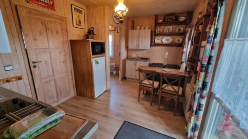 Intérieur cosy de petite maison en bois avec kitchenette, table à manger et décor rustique au Clos du Tay, La Gacilly