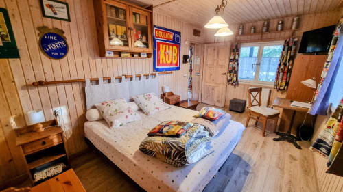 Chambre cosy en bois au B&B Le Clos du Tay à La Gacilly avec lit, enseignes vintage et décor rustique