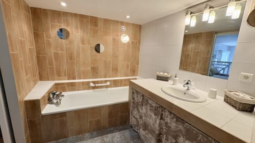 Salle de bain moderne à Entre vignes et dentelles avec murs en bois, lavabo blanc, baignoire et miroir à Courthézon