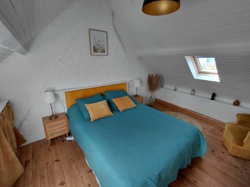 Chambre lumineuse au grenier avec lit turquoise, tête de lit orange et parquet au gîte Kergue'ch à Belle Île, Bretagne