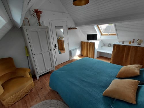 Chambre lumineuse sous les combles du gîte Kergue'ch, Belle Île en Mer, avec lit bleu, finitions bois, lucarne et équipements modernes