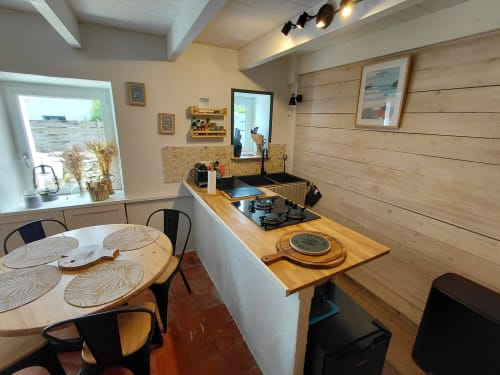 Cuisine cottage moderne avec coin repas, accents bois, cuisinière à gaz et vue sur le jardin à Sauzon