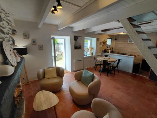 Séjour ouvert du gîte Kergue'ch, Belle Île en Mer, avec fauteuils en cuir tanné, tables d'appoint en bois, terracotta
