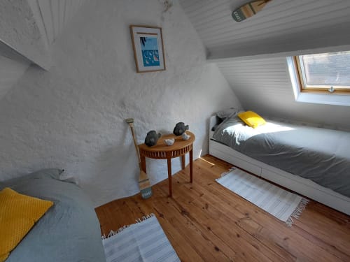 Chambre lumineuse sous les toits du gîte Kergue'ch, Belle Île en Mer, avec lit en bois, accents jaunes et lucarne