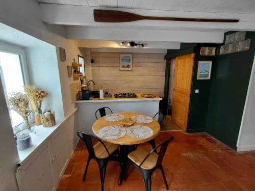 Cuisine ouverte et salle à manger du gîte Kergue'ch, Belle Île en Mer, avec table en bois, chaises noires et terracotta