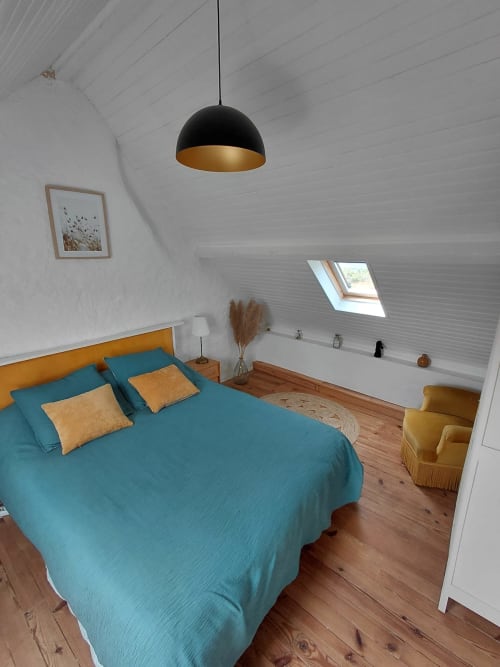Chambre mansardée moderne du gîte Kergue'ch avec lit bleu canard, suspension dorée et parquets