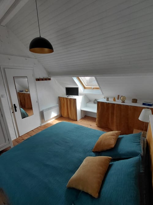 Chambre mansardée chaleureuse au gîte Kergue'ch, Belle Île-en-Mer : lits turquoise, finitions bois, fenêtres de toit et bureau de travail.