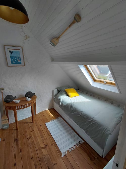 Chambre douillette sous les toits du gîte Kergue'ch, Belle Île en Mer, avec lucarne, lit en bois et oreiller jaune