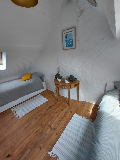 Chambre lumineuse de Loc'Maria, Belle Île avec planchers en bois, deux lits, tapis rayés et décor nautique
