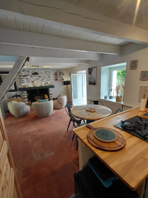 Cuisine ouverte et séjour avec poutres apparentes, cheminée, table à manger et vue sur le jardin à Sauzon, Belle Île