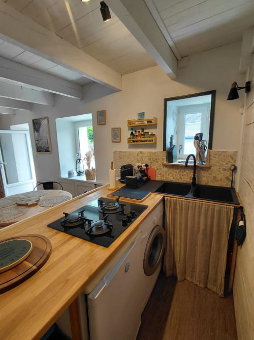 Cuisine moderne du gîte Kergue'ch, Belle Île en Mer, avec plan de travail en bois, cuisinière à gaz, évier noir et lave-linge