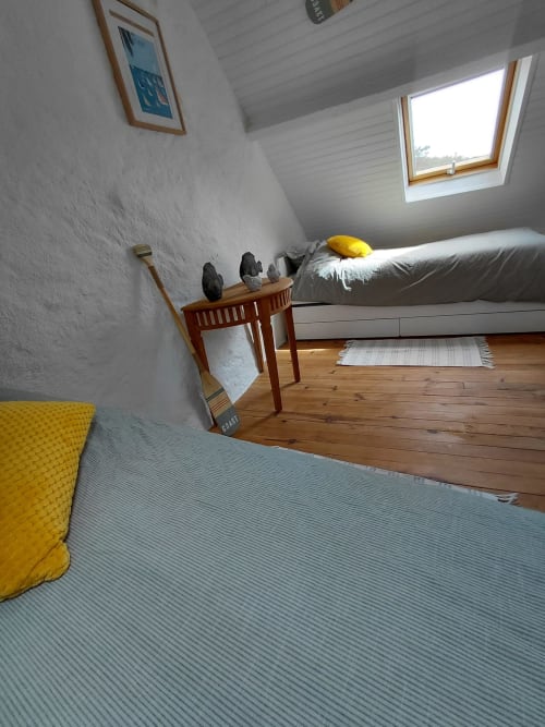 Chambre mansardée lumineuse avec lucarne, parquet, lit gris et coussin jaune au gîte de Kergue'ch