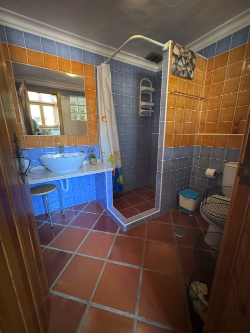 Banheiro colorido na T Monte Police House em Porto Côvo com pia azul, azulejos laranja e azul nas paredes e chuveiro tipo walk-in