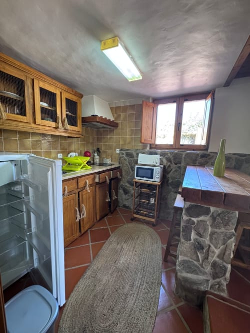 Cozinha do quarto Police House na Pousada Porto Côvo B&B, Portugal, com armários de madeira, eletrodomésticos e detalhes em pedra