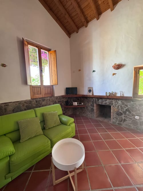 Sofá verde e lareira no quarto Police House da T Monte BnB, Porto Côvo