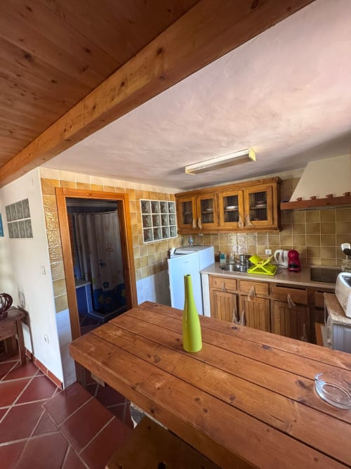 Cozinha rústica na Casa da Polícia de T Monte, Porto Côvo, com vigas de madeira, parede de azulejos e mesa de jantar