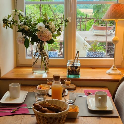 Table de petit-déjeuner avec fleurs fraîches, jus d'orange, pâtisseries et café à La Maison De Fleurat, vue sur le jardin