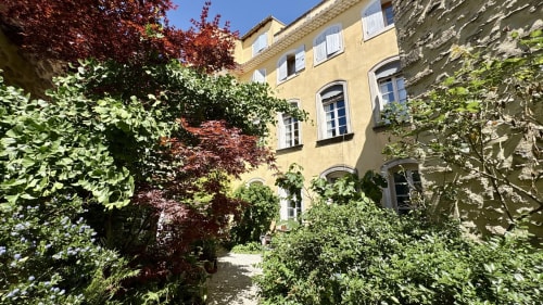 Cour luxuriante couverte de lierre à l'hôtel Entre vignes et dentelles à Courthézon, bâtiment en pierre jaune