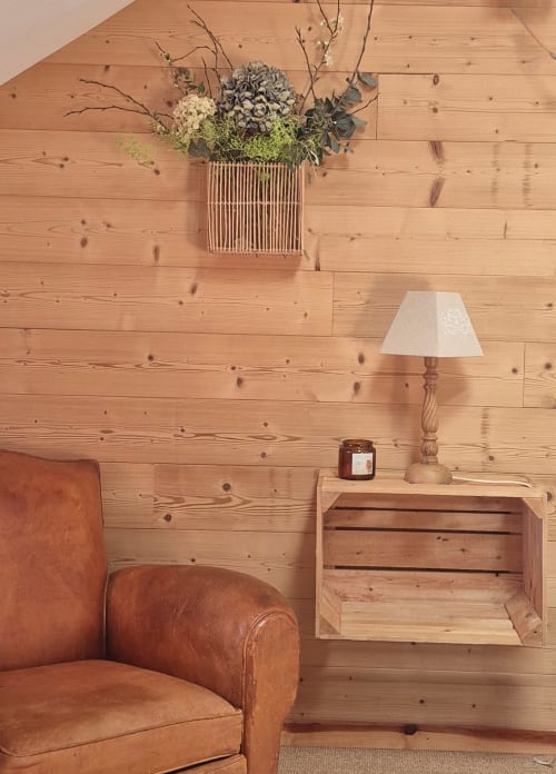Chambre rustique à La Maison De Fleurat avec fauteuil en cuir cognac, table de nuit en bois et mur de fleurs séchées
