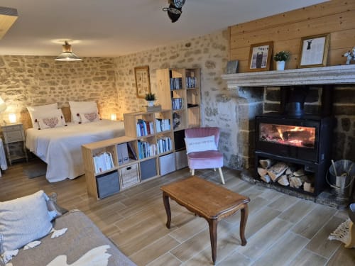 Chambre cosy en pierre à La Maison De Fleurat avec cheminée, lit, bibliothèque et vue sur le jardin à Domeyrot