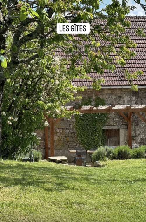 Jardin de charme d'une maison en pierre à La Maison De Fleurat à Domeyrot, avec murs couverts de lierre et pelouse verdoyante
