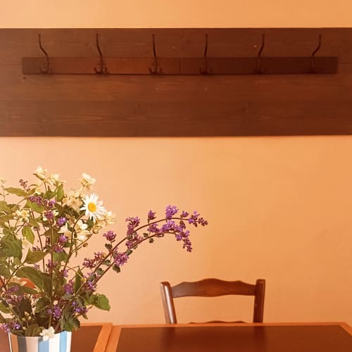 Chambre minimaliste à La Maison De Fleurat aux murs couleur pêche, porte-manteau en bois et fleurs fraîches à la villa L'Amandier