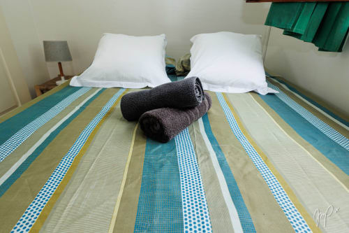 Chambre de la villa Kaz La Brise à Otantik Caribbean avec literie rayée, oreillers blancs et serviettes roulées, Le Gosier