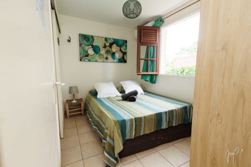 Chambre douillette du cottage Kaz La Brise à Otantik Caribbean, Le Gosier avec literie rayée, fenêtre vue jardin et décoration