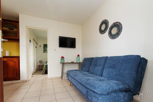Canapé bleu dans un cottage avec vue sur jardin à Otantik Caribbean, Le Gosier, avec téléviseur et assiettes décoratives murales