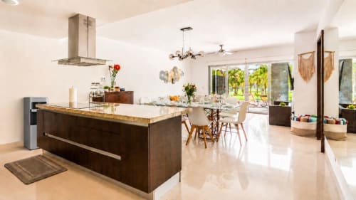 Moderna cocina abierta y comedor del Resort Mareazul Beachfront en Playa del Carmen con mueblería oscura e isla