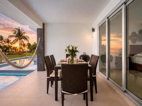 Comedor frente al mar con vista al atardecer, sillas de mimbre, piscina y palmeras en Mareazul Resort, Playa del Carmen