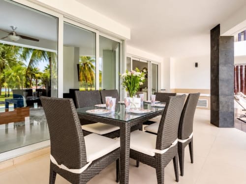Comedor moderno en Mareazul Resort Frente al Mar con sillas tejidas, mesa de cristal y vista a la piscina a través de amplios ventanales en Playa