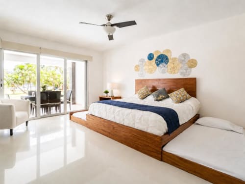 Luminosa habitación moderna en Mareazul Resort Beachfront con cama de madera, ventilador de techo y puertas con vista al océano en Playa del Carmen