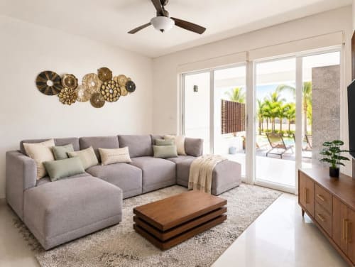 Sala moderna del Resort Mareazul frente al mar en Playa del Carmen, con sofá gris, mesa de madera y puertas con vista al océano