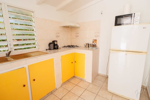 Cuisine moderne de la Villa Lueur du Sud à Otantik Caribbean avec armoires jaunes, cuisinière à gaz et réfrigérateur