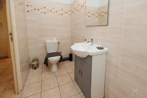 Salle de bain moderne avec lavabo blanc, toilettes et murs en carrelage beige à la Villa Lueur du Sud, Otantik Caribbean, Guadeloupe
